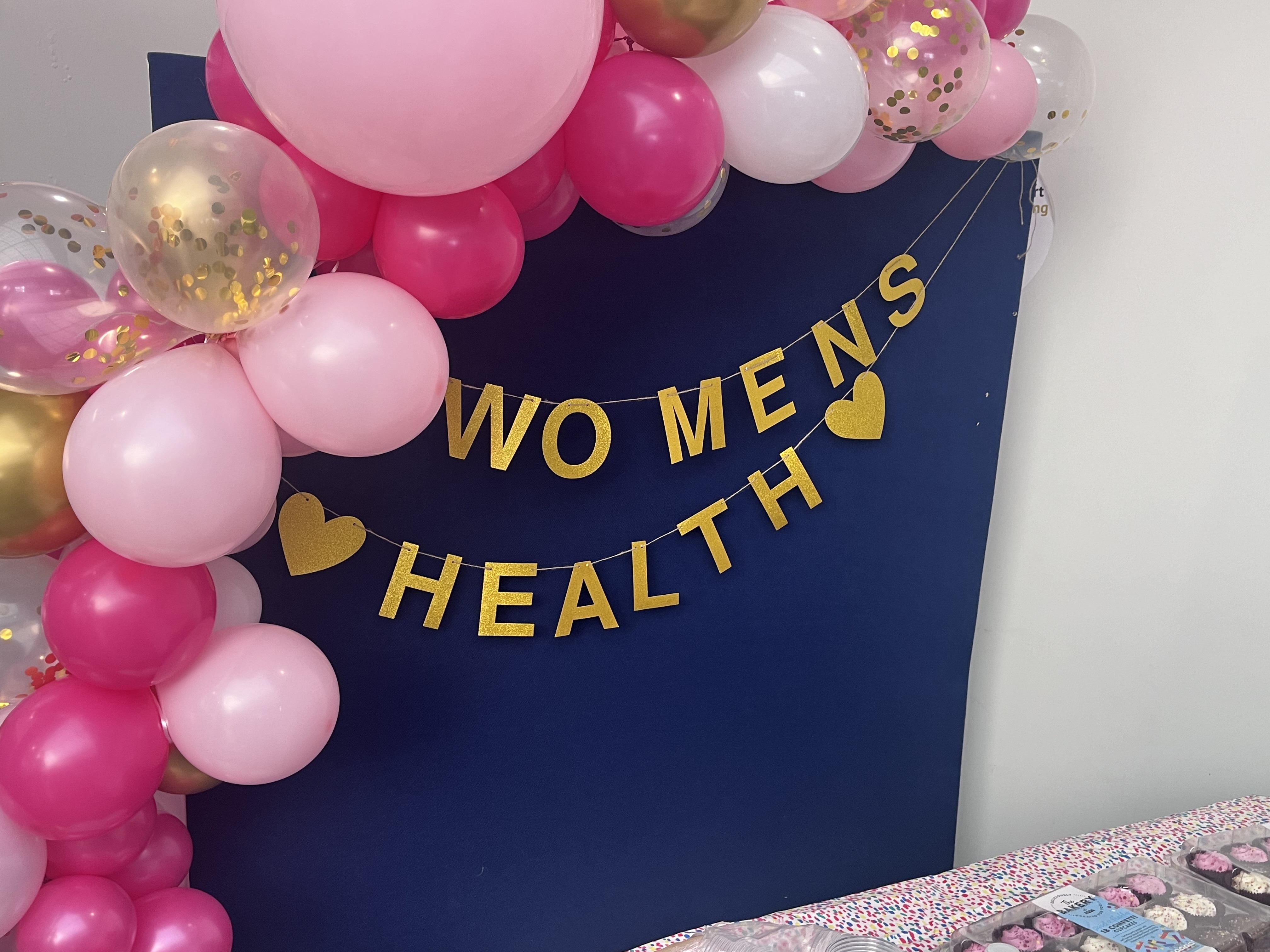 A photo of a gold banner that reads 'Women's health' with balloons