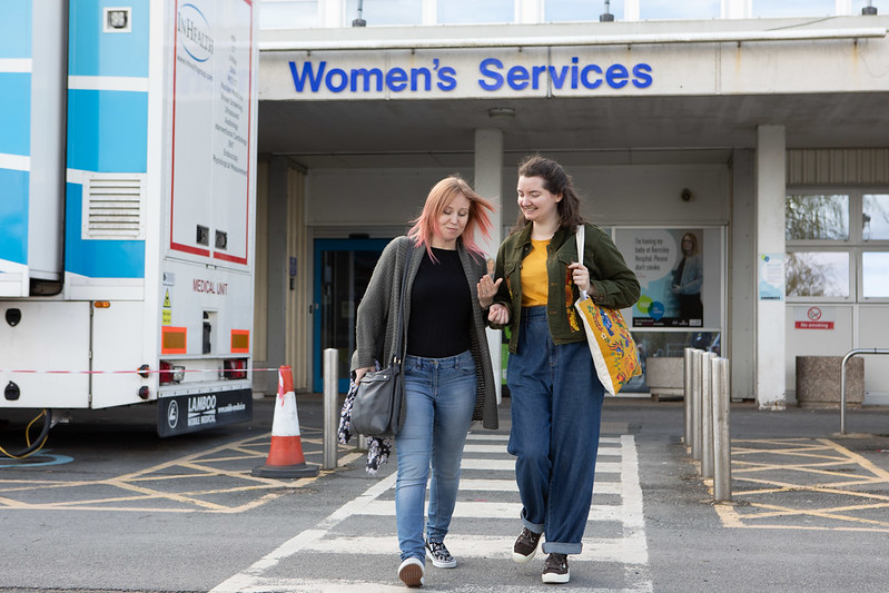 A photo of two women walking away from a hospital