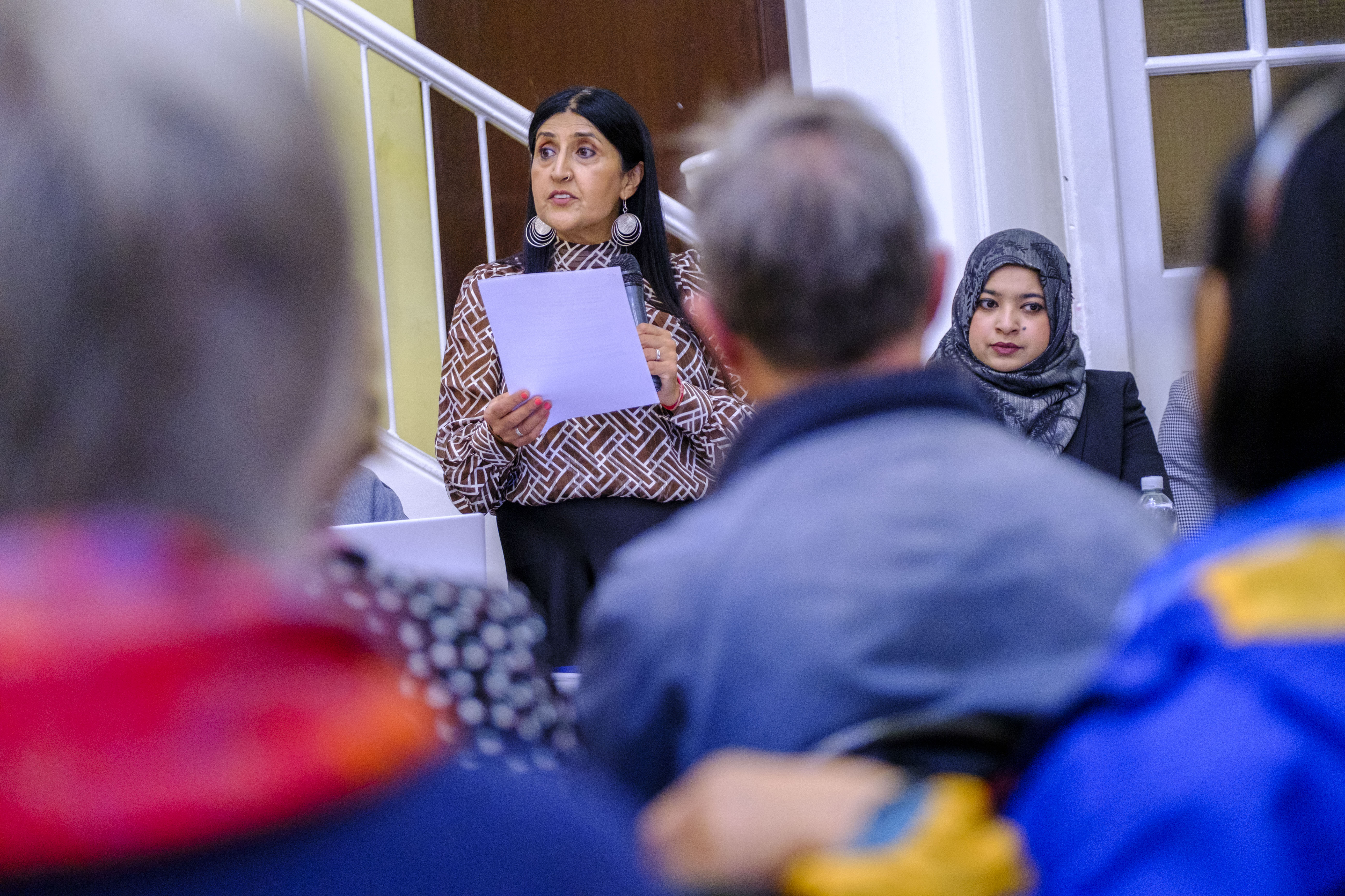 A photo of a woman stood in front of a crowd delivering a speech
