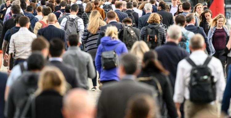 Large group of commuters walking over a bridge