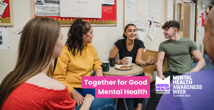 A group of young people sat around a table having tea and biscuits