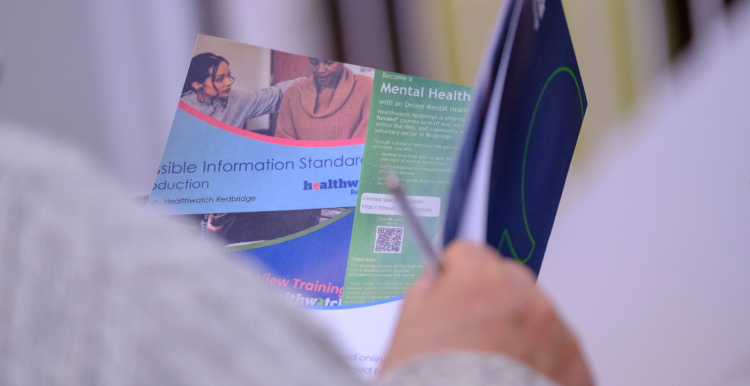 A photo of a person reading a document from Healthwatch Redbridge
