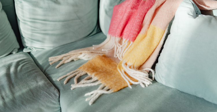 A photo of a sofa with a scarf or blanket thrown over it