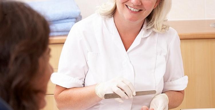 Woman smiling at another woman as she files her toe nails