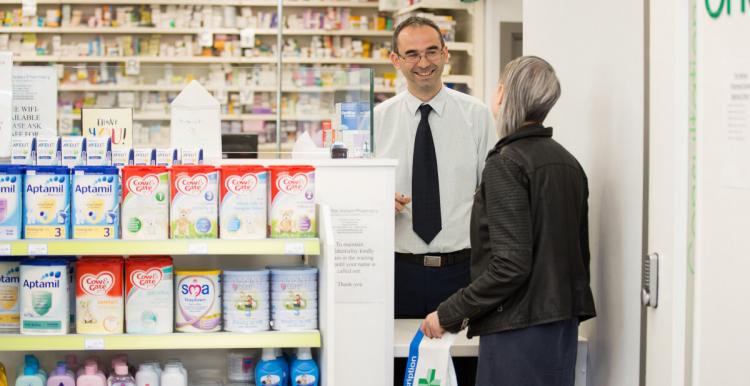 A woman talking to a male pharmacist