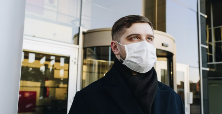Young man outside, wearing a blue surgical mask