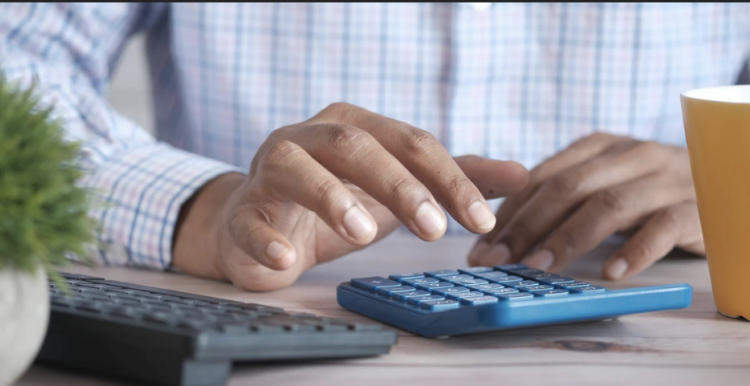 A man using a calculator to add up the monthly outgoings