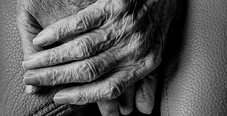 Close up of one elderly person's hands holding another hand
