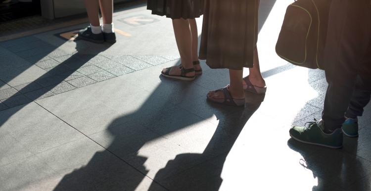 Peoples feet as they stand outside in a queue