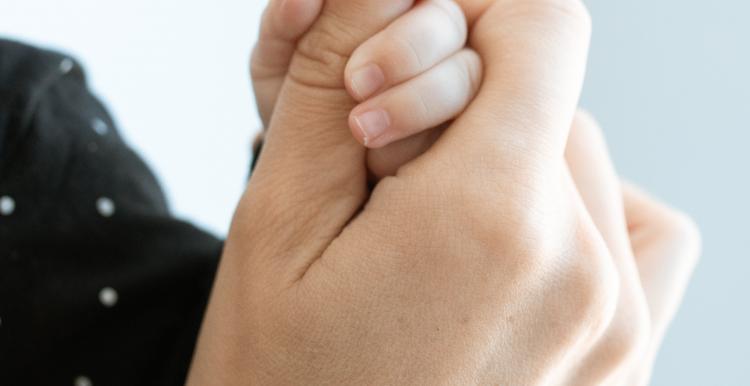 A baby holding an older person's hand