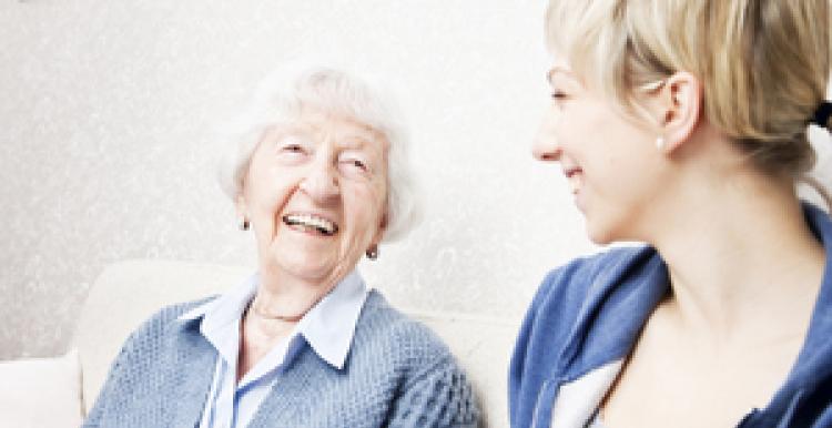 An elderly woman laughing with a young female care home assistant
