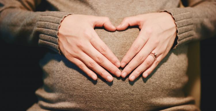 pregnant lady with hands over her stomach in a heart shape