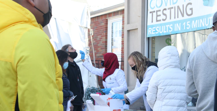 A group of people on the street waiting to have rapid covid test