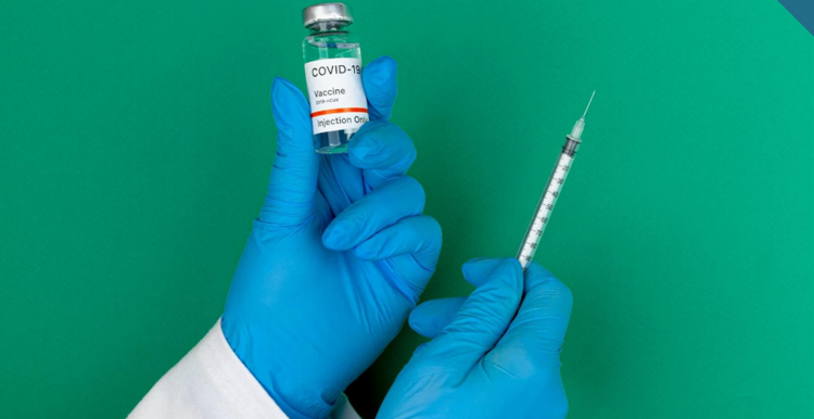 Hand holding and vaccine bottle and a syringe