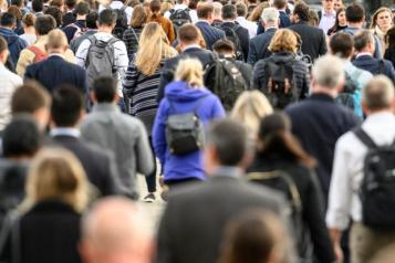 Large group of commuters walking over a bridge