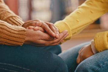 A close up photo of someone holding another person's hands in a supportive manner