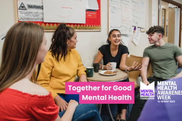 A group of young people sat around a table having tea and biscuits