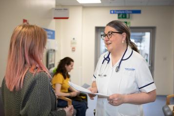 A photo of medical professional talking to a woman in a waiting room.