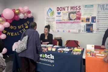 A photo of a Healthwatch Redbridge stall next to a sign that reads 'Women's Health'.