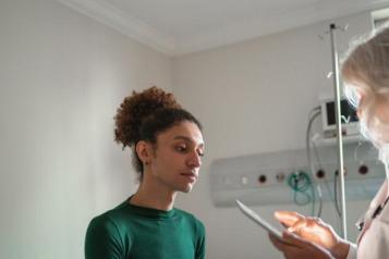 A photo of a person in a medical room talking to a doctor