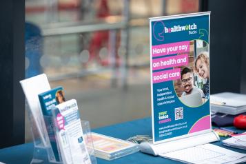 A photo of a healthwatch stall with a poster that reads 'have your say on health and social care'