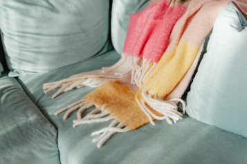A photo of a sofa with a scarf or blanket thrown over it