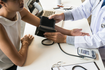 A photo of a woman with a doctor who is taking her blood pressure