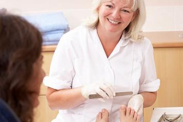 Woman smiling at another woman as she files her toe nails