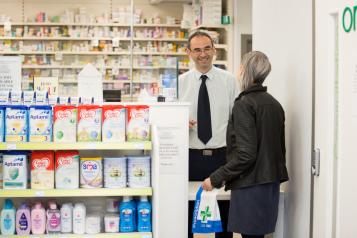 A woman talking to a male pharmacist