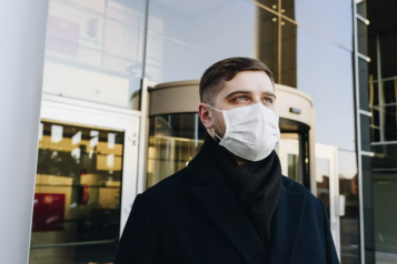 Young man outside, wearing a blue surgical mask