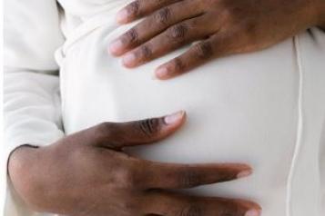 Close up of black pregnant woman's hands supporting her stomach