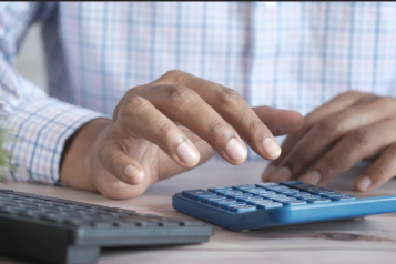 A man using a calculator to add up the monthly outgoings
