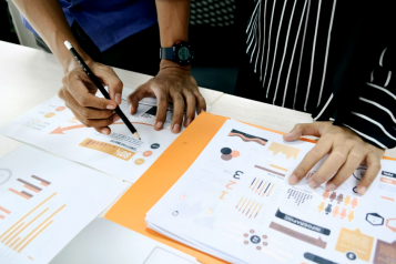 Two people looking at some data graphs on a desk