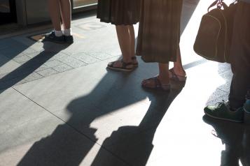 Peoples feet as they stand outside in a queue