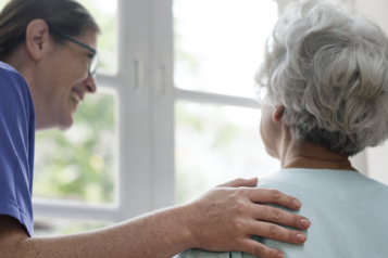 An elderly female patient talking to a nurse, overlooking a hospital window