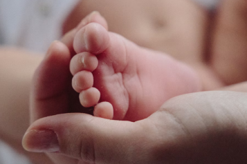 Close up of mother's hands holding new born baby's feet 