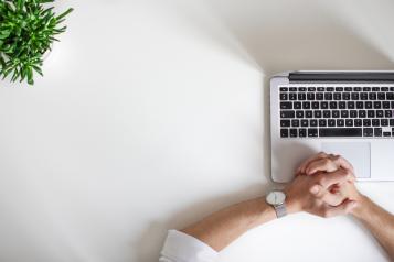 A person looking at their laptop, waiting