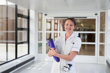 Smiling nurse with a clipboard in a hospital corridor