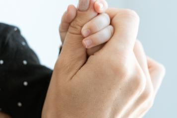 A baby holding an older person's hand