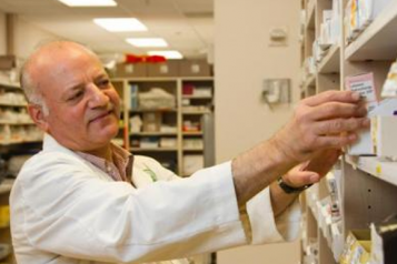 Pharmacist taking medication from off the shelf