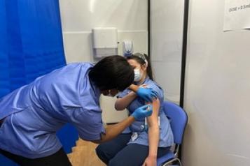A female nurse giving another female nurse a vaccination