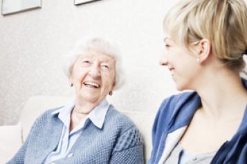 An elderly woman laughing with a young female care home assistant