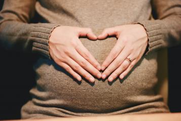 pregnant lady with hands over her stomach in a heart shape