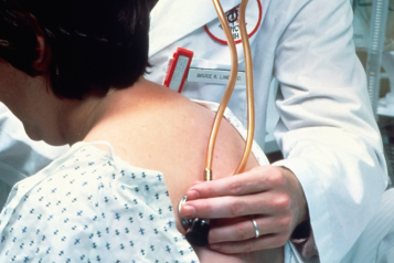 A male DR listening to the lungs of a patient through a stethoscope on her back