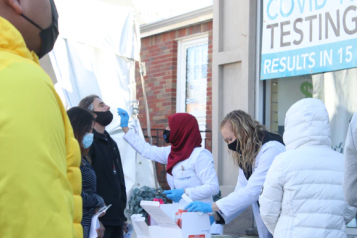 A group of people on the street waiting to have rapid covid test