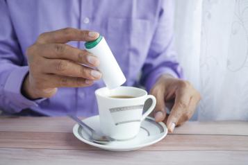 A person putting a sugar substitute in their tea