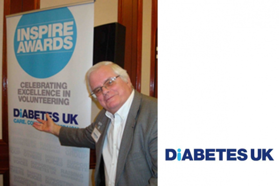 A male member of Diabetes UK at an event pointing towards their pull up banner