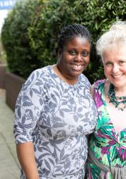 Two women stood in a courtyard with their arms round each other