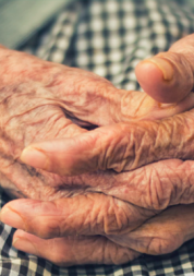 Close up image of an elderly woman's hands clasped on her knees